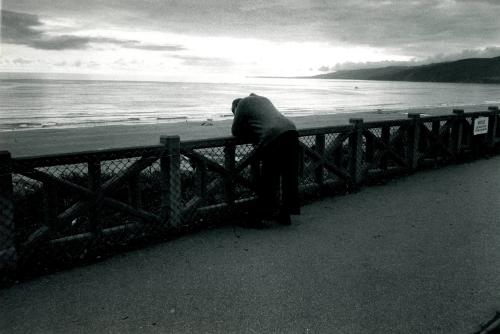 Man leaning on railing at beach